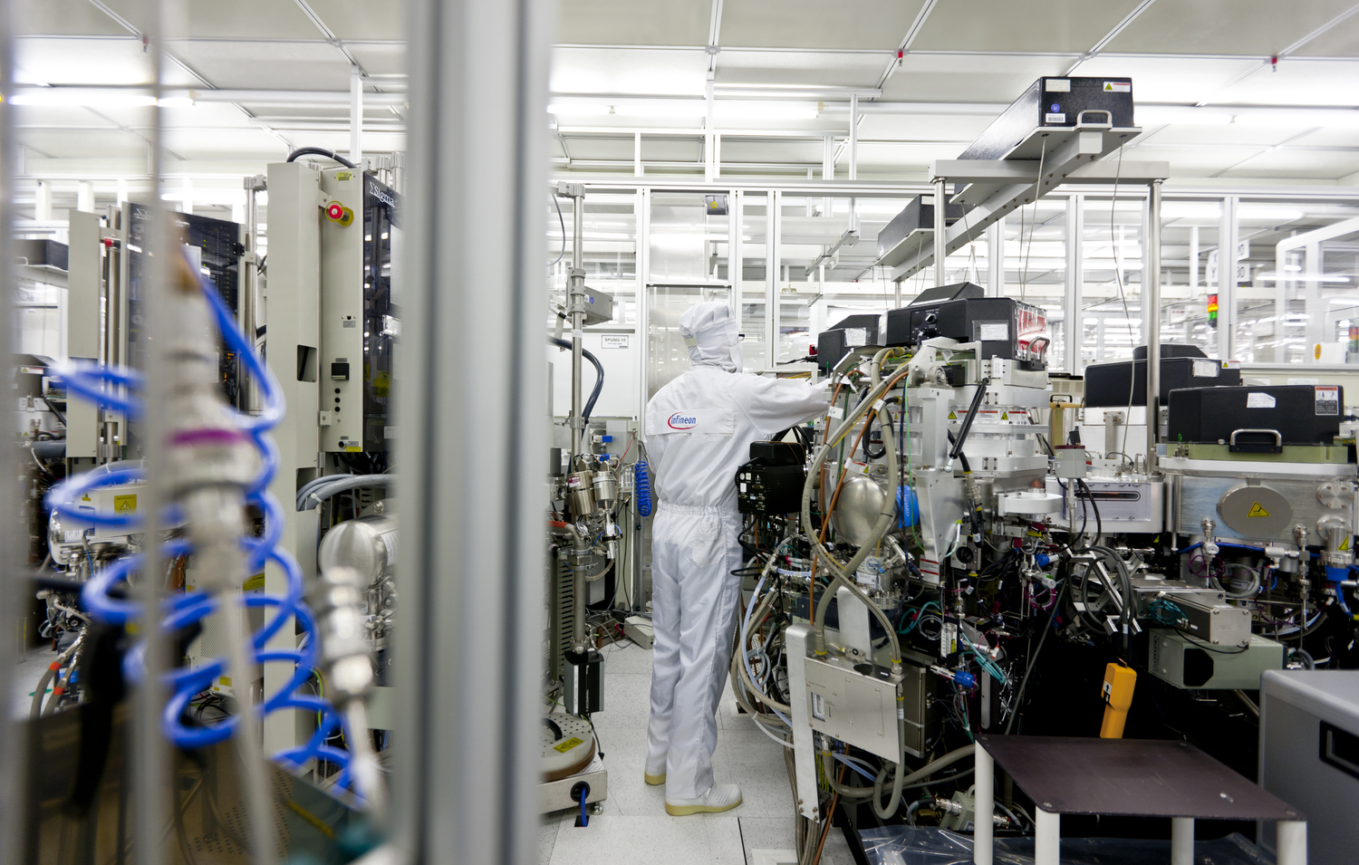 An Infineon Technologies adjusts equipment in a semiconductor cleanroom in Dresden Germany Image courtesy of Infineon