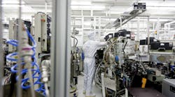 An Infineon Technologies adjusts equipment in a semiconductor cleanroom in Dresden, Germany. (Image courtesy of Infineon).