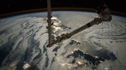 The robotic arm from the International Space Station can be seen over Earth.