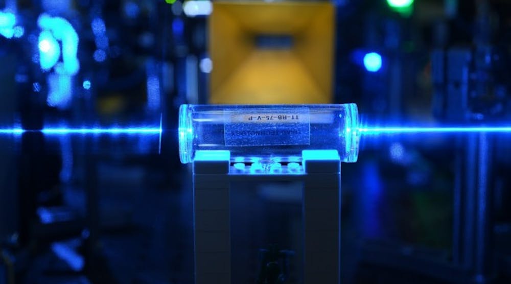 Atoms in a glass vapor cell are excited with laser beams to Rydberg states. They detect the electric fields coming from the gold antenna in the background and imprint the information back onto the laser beams.