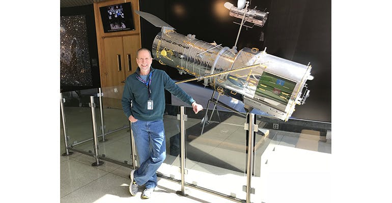 2. The HST lead optical telescope system engineer, Mike Wentz, and his team have developed a new method for pointing the orbiting space telescope. Wentz poses next to a model of the HST.